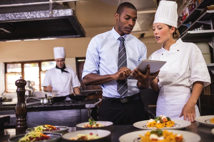 manager and chef using digital tablet in kitchen at hotel