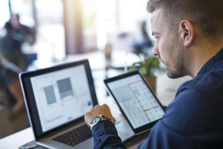 human analyzing projects on his laptop computer and tablet.