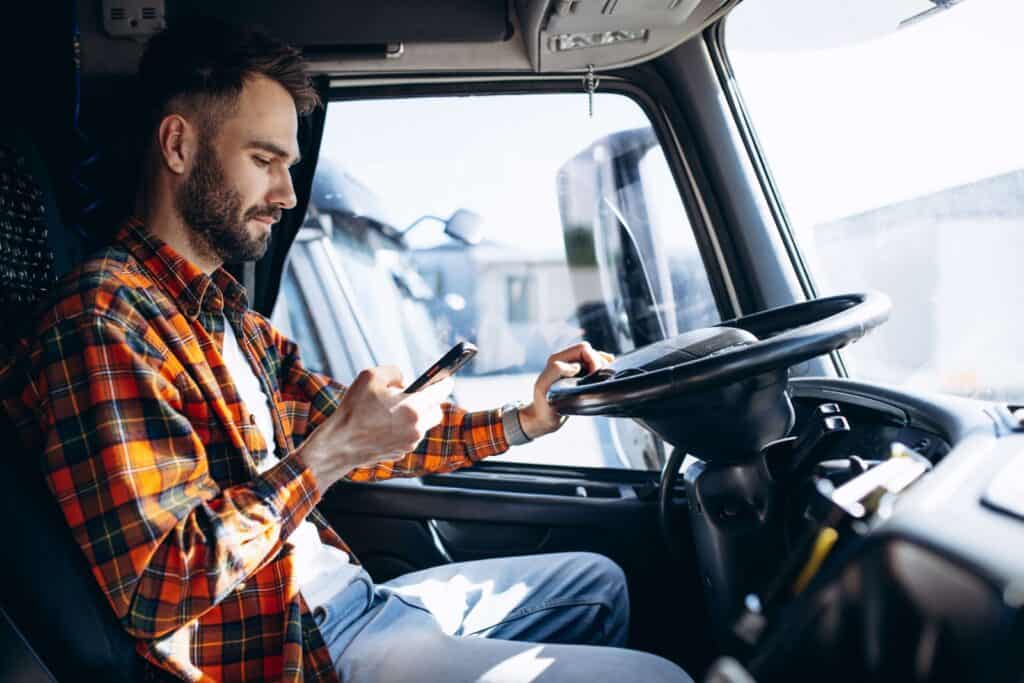 truck driver looking at app on phone in truck, not moving