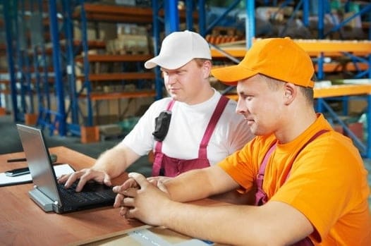 Two workers looking at laptop in warehouse