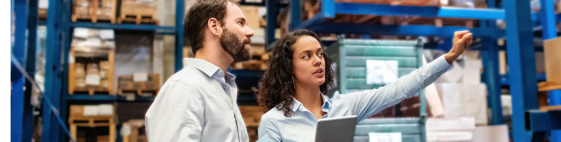 a man and a woman reviewing warehouse inventory